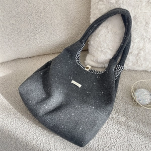 Détail d'un sac cabas en feutre gris avec motifs étoiles et doublure à carreaux