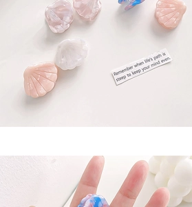 Macro detail of shell-shaped acetate hair clips in pink, white, and blue-purple colors