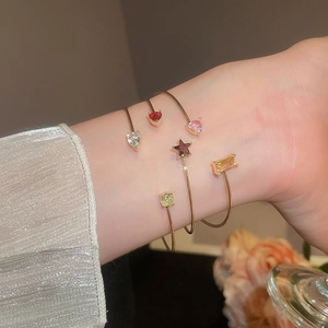 Detail of layered gold bangles set with colorful zircon stones worn on the wrist