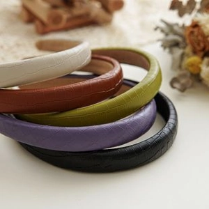 Dettaglio di cinque elastici per capelli con trama a coccodrillo in colori neutri e pastello