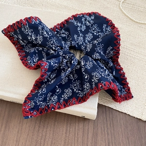 Detail of vintage navy blue floral fabric headband with red cross-stitch embroidery edge
