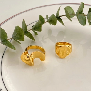 Close-up of wavy gold stainless steel rings on a white porcelain dish with eucalyptus