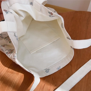 Détail de l'intérieur du sac en toile fleurie montrant la poche de rangement interne