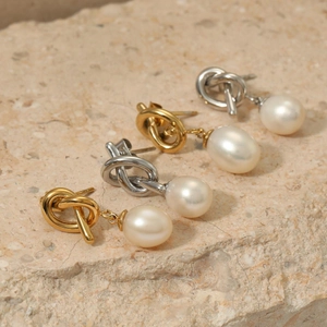 Elegant freshwater pearl drop earrings with gold and silver knot studs on stone