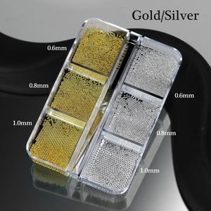 Macro detail of gold and silver nail art caviar metal beads in a six-grid plastic storage box