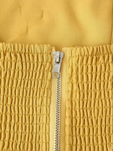 Gros plan détaillé d'un tissu jaune smocké avec une fermeture éclair en argent pour robe