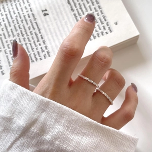 Minimalist S925 sterling silver textured rings worn by hand on a book background