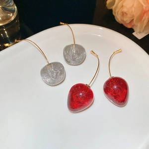 Gros plan de boucles d'oreilles cerises avec breloques en résine rouge et crochets dorés