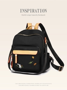 Detail of color-block nylon backpack featuring rabbit embroidery and leather flap