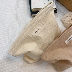 Detail of striped textured cotton makeup bags with simple wish labels on soft fabric