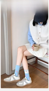 Detail of light blue crew socks featuring cute cartoon cat motifs and pink wavy patterns