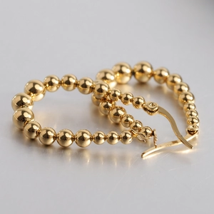 Macro shot of gold stainless steel beaded hoop earrings in a heart-shaped arrangement