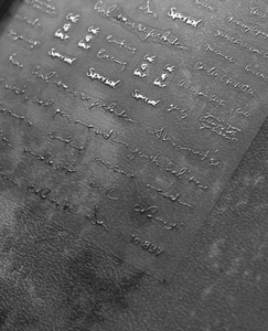 Detail of white cursive lettering stickers for nail art on a dark textured background