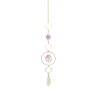 Macro detail of hanging crystal ornament with purple raw stone and golden metal frames