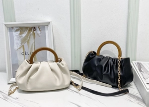 Detail showing soft ruched texture and natural wood handle of the cloud crossbody bag