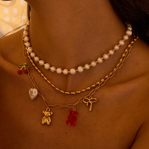 Layered gold necklace featuring pearls, cherry and bear charms on a female model
