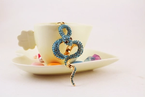 Detailed view of a gold snake keychain with blue rhinestones on a ceramic cup handle