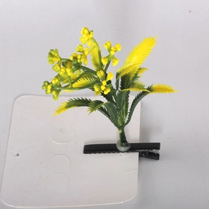 Detail of a handmade floral hair clip with yellow petals and green leaves on black clip
