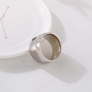 Detailed close-up of a wide polished stainless steel ring on a decorative ceramic tray