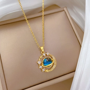 Dettaglio collana in oro con ciondolo a pianeta, gemma blu e diamanti in scatola regalo