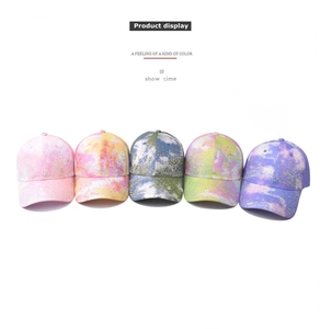 Close-up of five colorful tie-dye baseball caps with rhinestone bear designs on white background