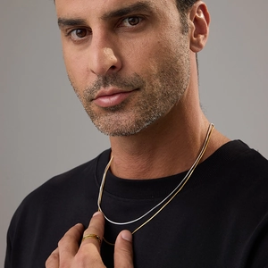 Detail of layered gold and silver snake bone chain necklaces worn by a model