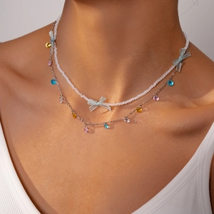 Detailed close-up of double-layer beaded necklace with blue bow and colorful heart pendants