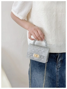Detail of glitter PVC jelly bag featuring a beaded handle and gold chain strap
