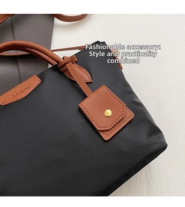 Close-up of black nylon tote with brown leather trim and golden metal snap button
