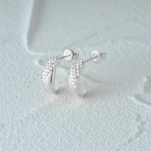 Detail of silver C-shape stud earrings featuring white cubic zirconia pavé stones