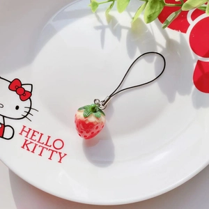 Detail of a realistic red strawberry charm with green leaves and black braided lanyard cord