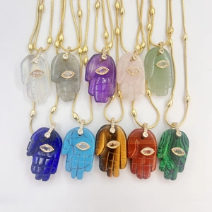 Detalle de collares Mano de Fátima en piedras naturales de colores con dijes del Ojo del Mal