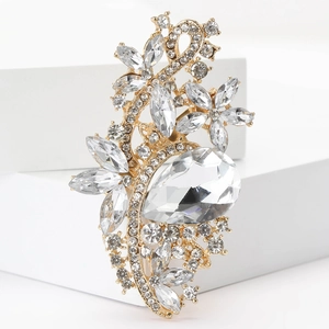 Detail view of a golden vintage floral brooch with clear rhinestones on a white pedestal