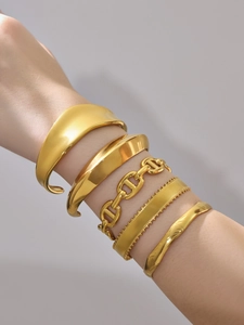 Detalle de cinco brazaletes y pulseras de cadena de acero inoxidable bañados en oro 18k