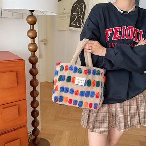 Detail of plush beige bucket bag featuring colorful 3D patches and dual handles