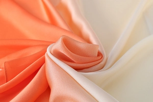 Detail eines Seidenschals mit sanftem Farbverlauf von Orange nach Beige und Seidenglanz