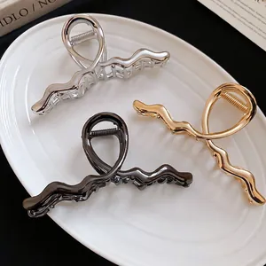 Set of wavy metallic hair clips in gold, silver and black finish on a white plate
