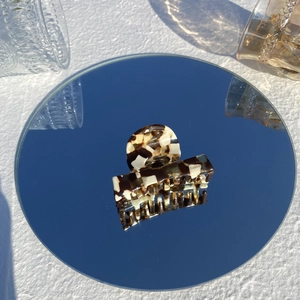 Detailed view of a tortoise shell hair claw clip reflecting on a round mirror