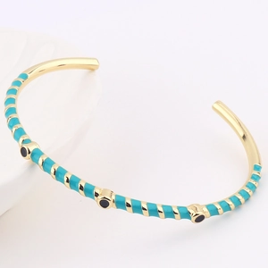 Detail of gold-plated bangle with turquoise enamel and black stone dots decoration