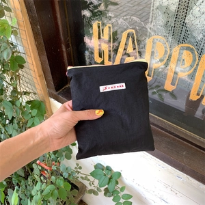 Handheld view of a compact black nylon mini organizer bag with zipper and brand logo