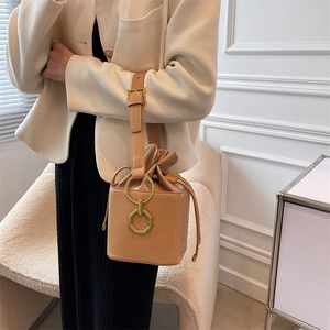 Vintage khaki leather bucket bag with drawstring closure and golden metal ring details