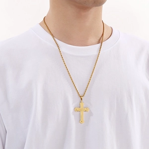 Close-up of a double-layered gold cross pendant necklace on a gold rope chain
