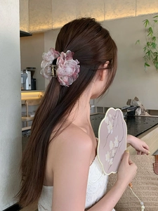 Dettaglio di un fermaglio per capelli con fiore in tessuto a rete rosa su acconciatura