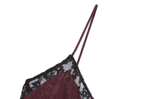 Detailed close-up of dark red satin fabric with black lace trim and thin shoulder straps