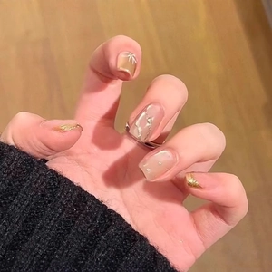Short square press-on nails with nude pink base, gold foil, 3D bows, and pearls
