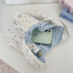 Vista interna della borsa in tela floreale con pizzo blu e accessori di cancelleria estetica