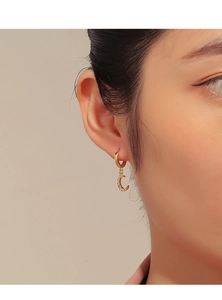 Detailed view of a gold moon drop earring with zircon stones worn by a model