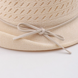 Close-up of beige woven sun hat featuring a delicate leather bow and breathable texture