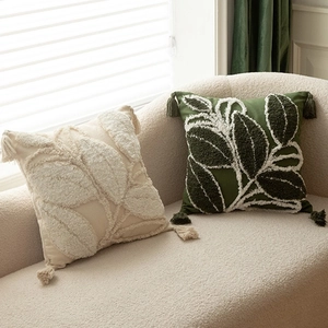 Floral embroidered throw pillows in beige and green with leaf tufting and corner tassels