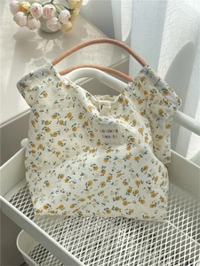 Floral canvas tote bag detail with woven handles and branded label in a soft setting